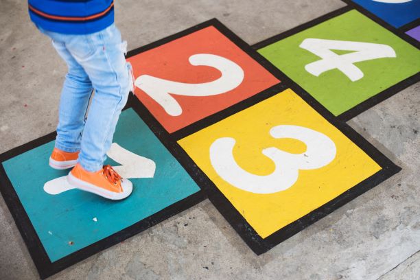 young kid playing hopscotch