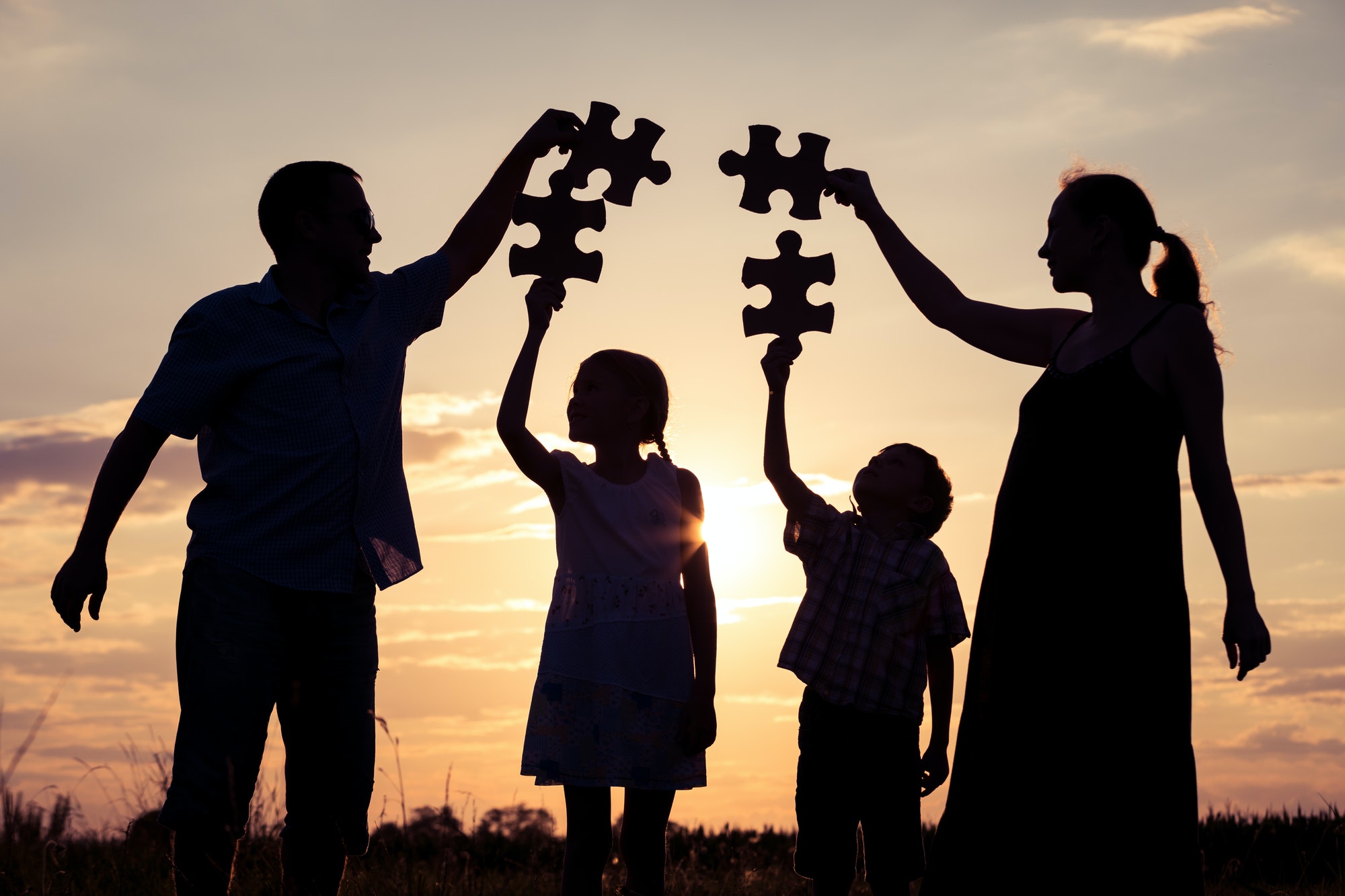 Happy family standing in the park at the sunset time.